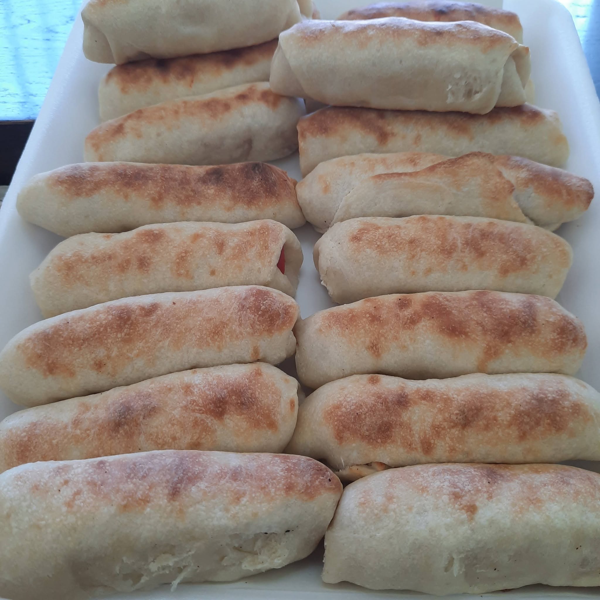 Hot dog pastry rolls arranged on a tray.